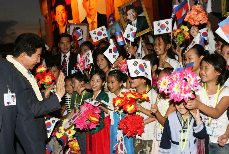 [캄보디아 공식환영식에서 태극기를 흔드는 어린이들의 손을 잡아주는 노무현 대통령]