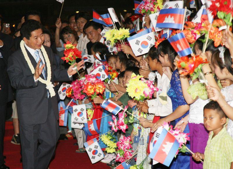 [캄보디아 공식환영식에서 태극기를 흔드는 어린이들의 손을 잡아주는 노무현 대통령]