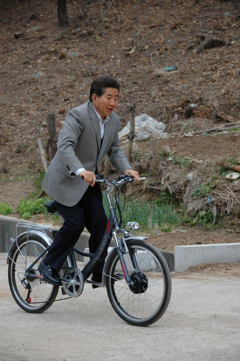 [봉하마을을 방문한 카이스트 학생들과 기념촬영하기 위해 자전거 타고 이동하는 노무현 전 대통령]