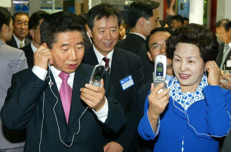 [ITU 텔레콤 아시아 2004 전시장에서 전시 핸드폰을 사용해 보는 노무현 대통령 내외]