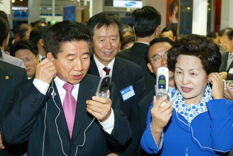 [ITU 텔레콤 아시아 2004 전시장에서 전시 핸드폰을 사용해 보는 노무현 대통령 내외]