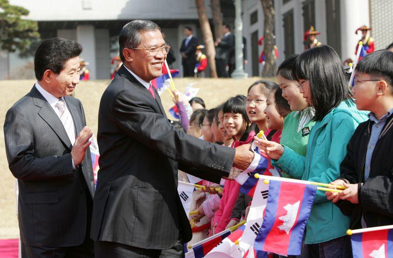 [캄보디아 총리 공식환영식에서 양국 국기를 흔드는 어린이들의 환영을 받는 양국 정상]